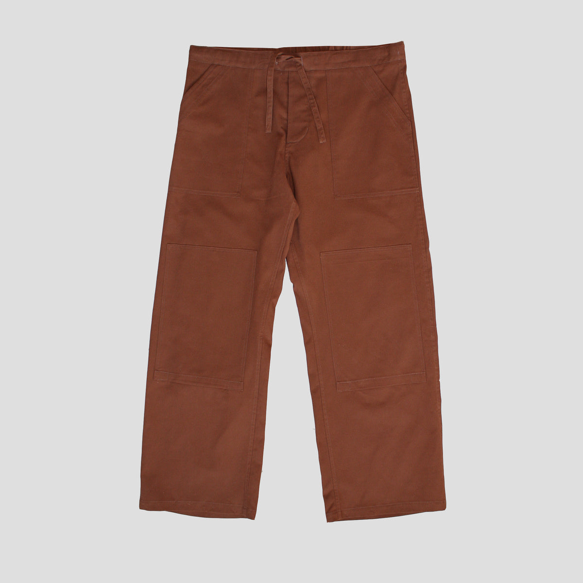 A pair of brown drawstring chore trousers made of rustic cotton canvas, featuring reinforced seams, deep front pockets, and a button fly.